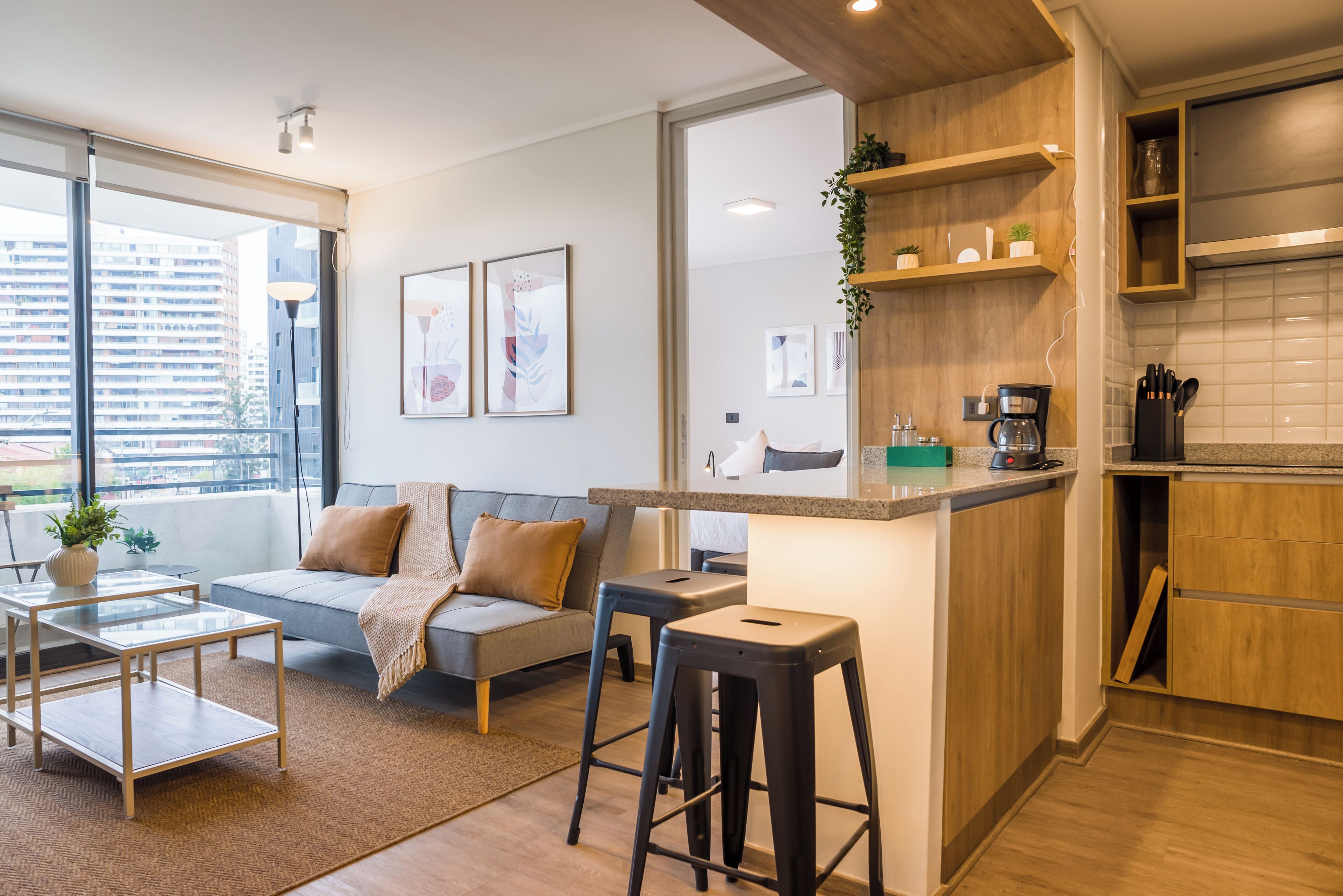 Un appartement moderne comprenant un espace de vie, une kitchenette et une grande fenêtre donnant sur la ville.