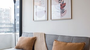 A modern living room with a grey sofa, two brown cushions, and a knitted throw. - Beautiful Apt in Las Condes with Pool (Las Condes)