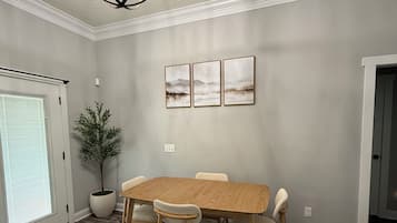Una sala da pranzo con un tavolo e sedie in legno, un lampadario e tre quadri appesi al muro.
