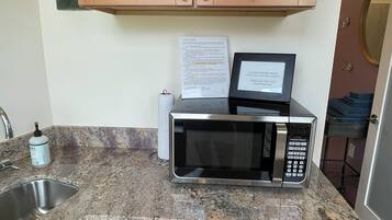 A compact kitchen with wooden cabinets, a microwave, a dishwasher, and a sink.