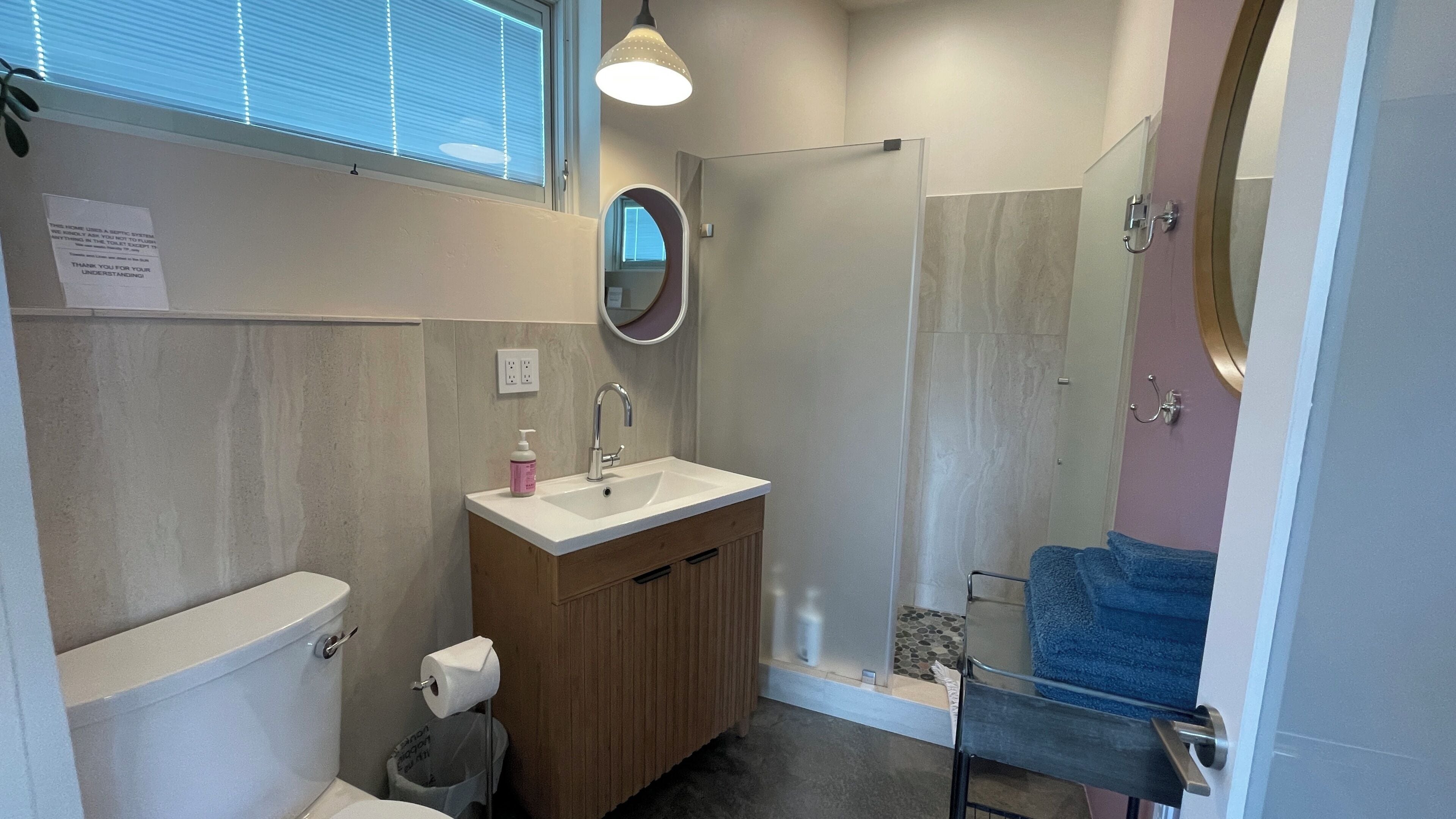 Une salle de bain équipée de toilettes, d’un lavabo, d’un miroir et d’une douche.
