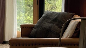 A room with a large window, a cushioned bench, and a wooden table.