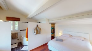 Ein Schlafzimmer mit Bett, Nachttisch und einem Badezimmer mit Toilette und Handtuchhalter.