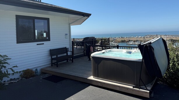 A hot tub on a wooden deck with a view of the ocean. - The White Haus (Brookings)