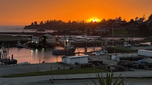 A marina with boats docked, a building with a red roof, and a sunset in the background. - The White Haus (Brookings)