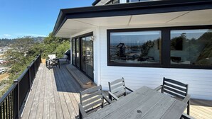 A modern house with a deck, large windows, and a view of a cityscape. - The White Haus (Brookings)