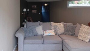 A living room with a grey sectional sofa, a lamp, and a window.