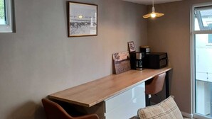 Un espacio habitable moderno con una larga mesa de madera, un sofá con varios cojines y un cuadro en la pared.
