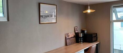 Un espacio habitable moderno con una larga mesa de madera, un sofá con varios cojines y un cuadro en la pared.