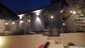 Una casa moderna con esterno scuro, una scala ben visibile e una sedia rossa all'esterno.
