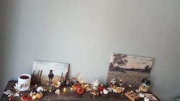Ein Holztisch mit herbstlichen Dekorationen, darunter Kürbisse, Tannenzapfen und eine Kerze.