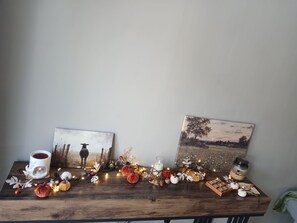 Una mesa de madera decorada con motivos otoñales, incluyendo calabazas, piñas y una vela.