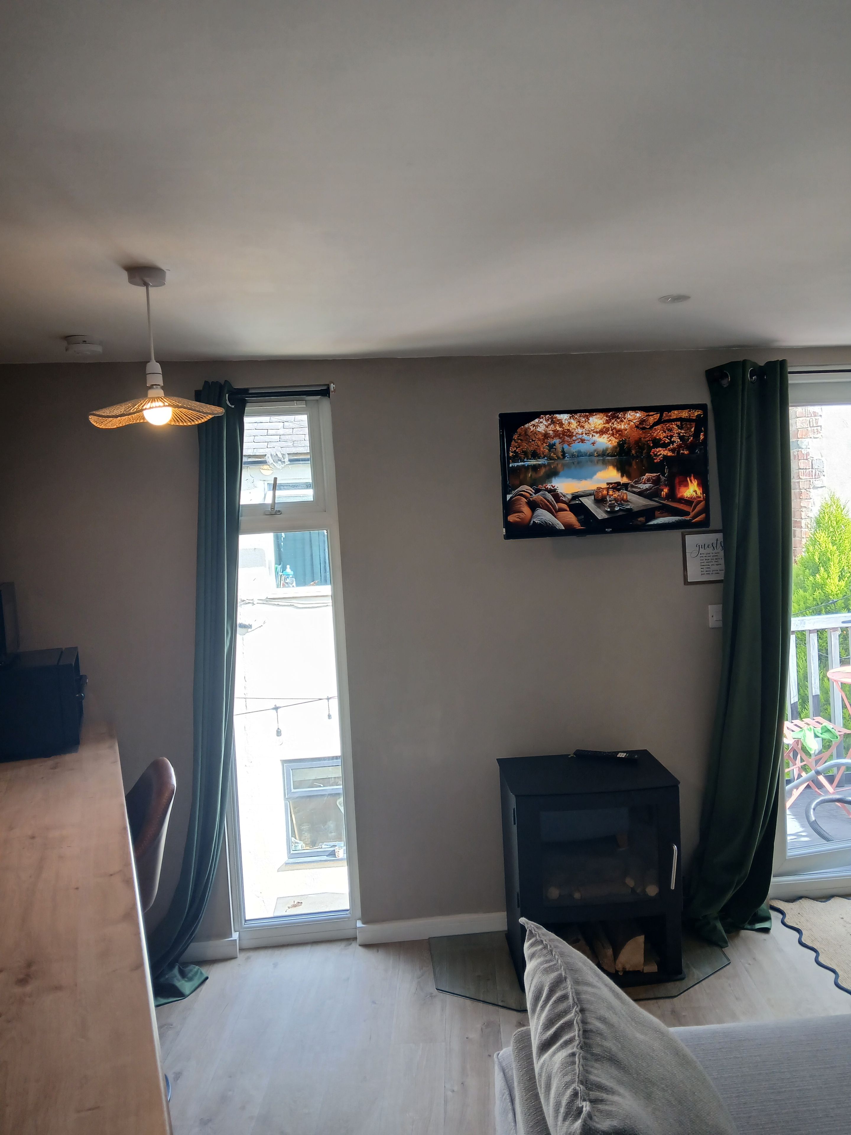 Een woonkamer met een televisie, een open haard en uitzicht op een balkon.