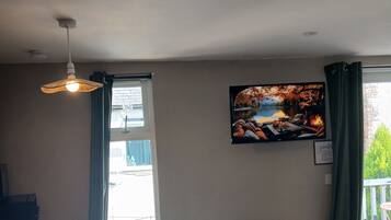 Een woonkamer met een televisie, een open haard en uitzicht op een balkon.