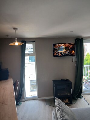 A living room with a television, a fireplace, and a view of a balcony.