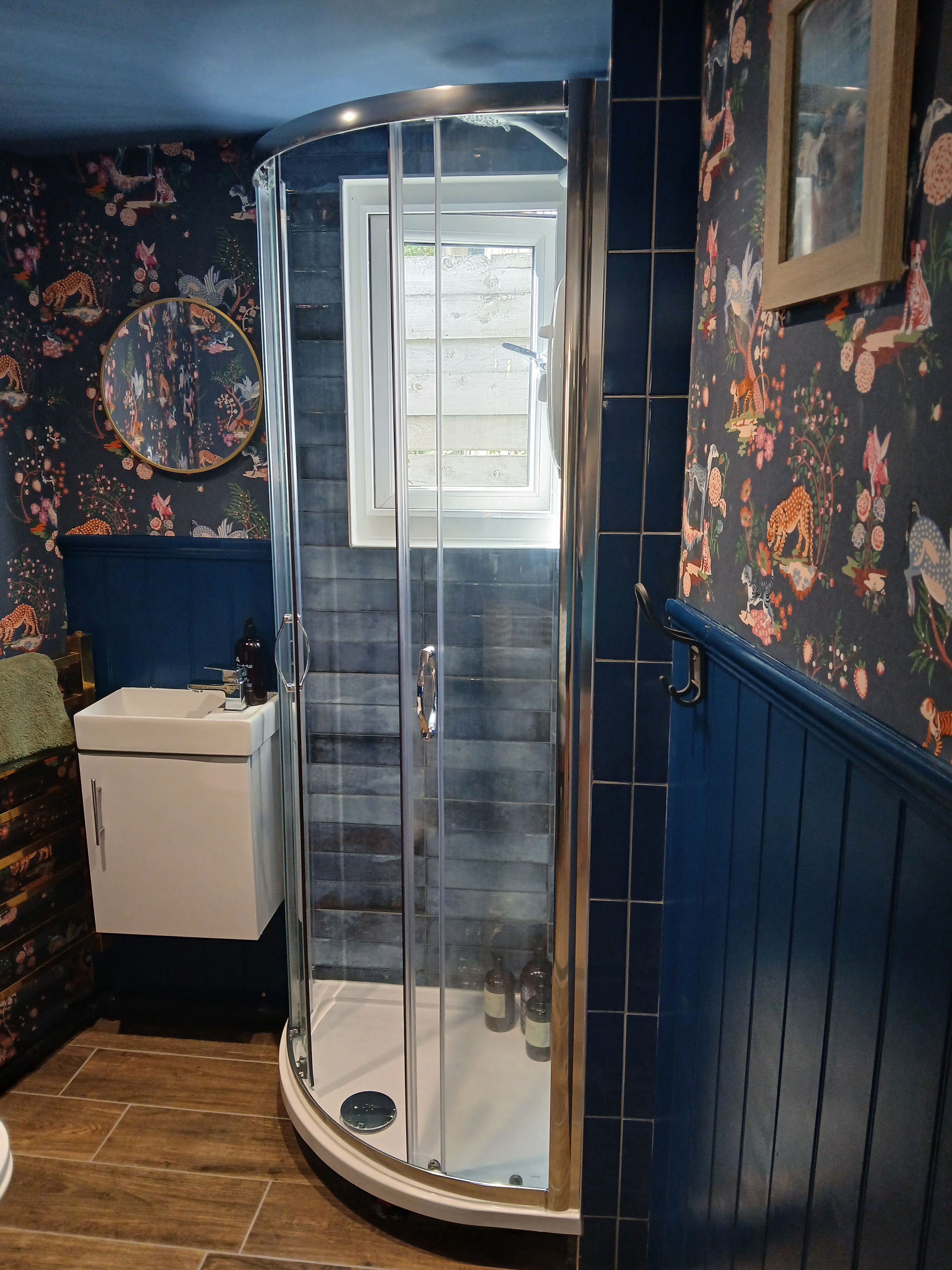 A bathroom with a glass shower enclosure, a sink, and a mirror.