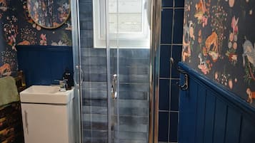 A bathroom with a glass shower enclosure, a sink, and a mirror.