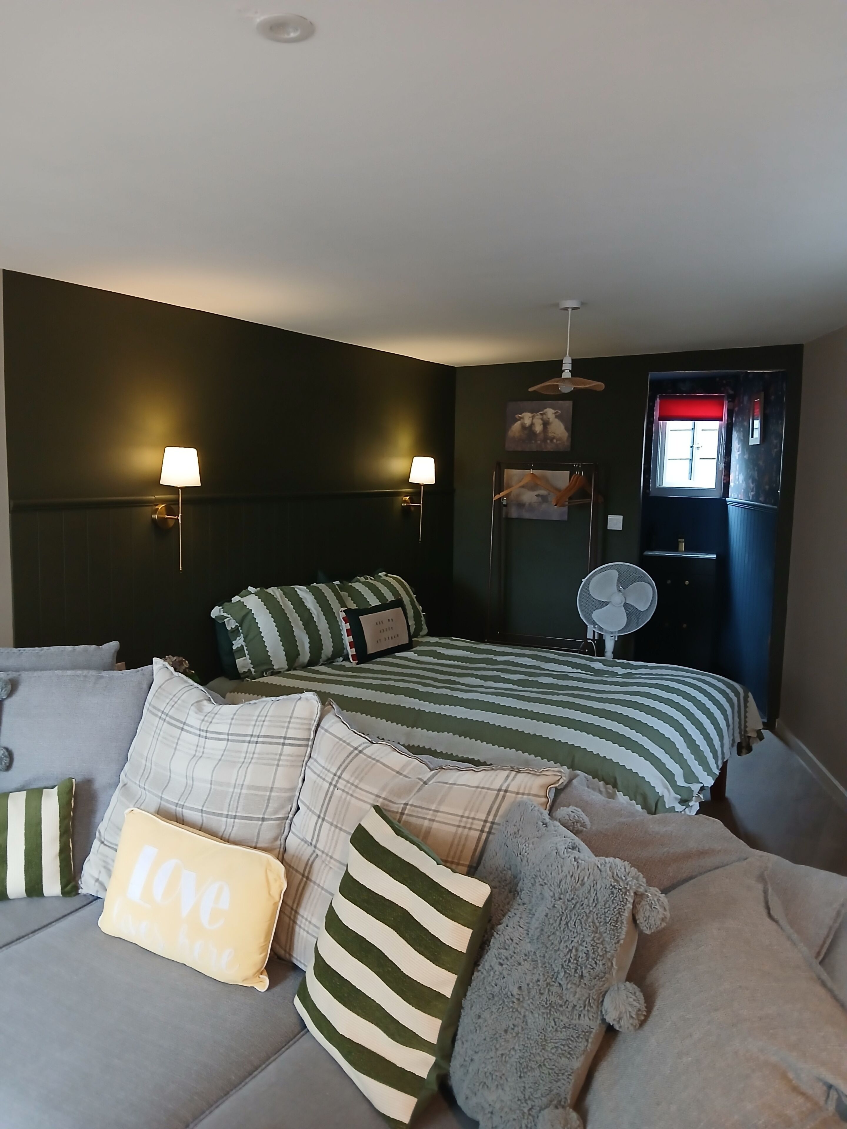 A bedroom with two beds, a sofa, and a fan.