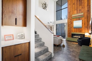 A modern interior with a wooden staircase, a fireplace, and a seating area.