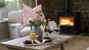 Una sala de estar acogedora con chimenea, una mesa de comedor con una botella de vino, copas, queso y uvas.