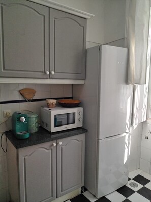A compact kitchen with grey cabinets, a white refrigerator, a microwave, and a kettle on the countertop. - Apartment near Feira da Ladra & Alfama (Lisboa)
