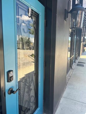 A blue door with a keypad lock, a glass panel, and a decorative metal design.