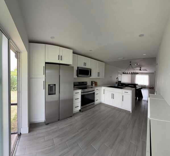 A modern kitchen with white cabinetry, stainless steel appliances, and a herringbone wood floor.