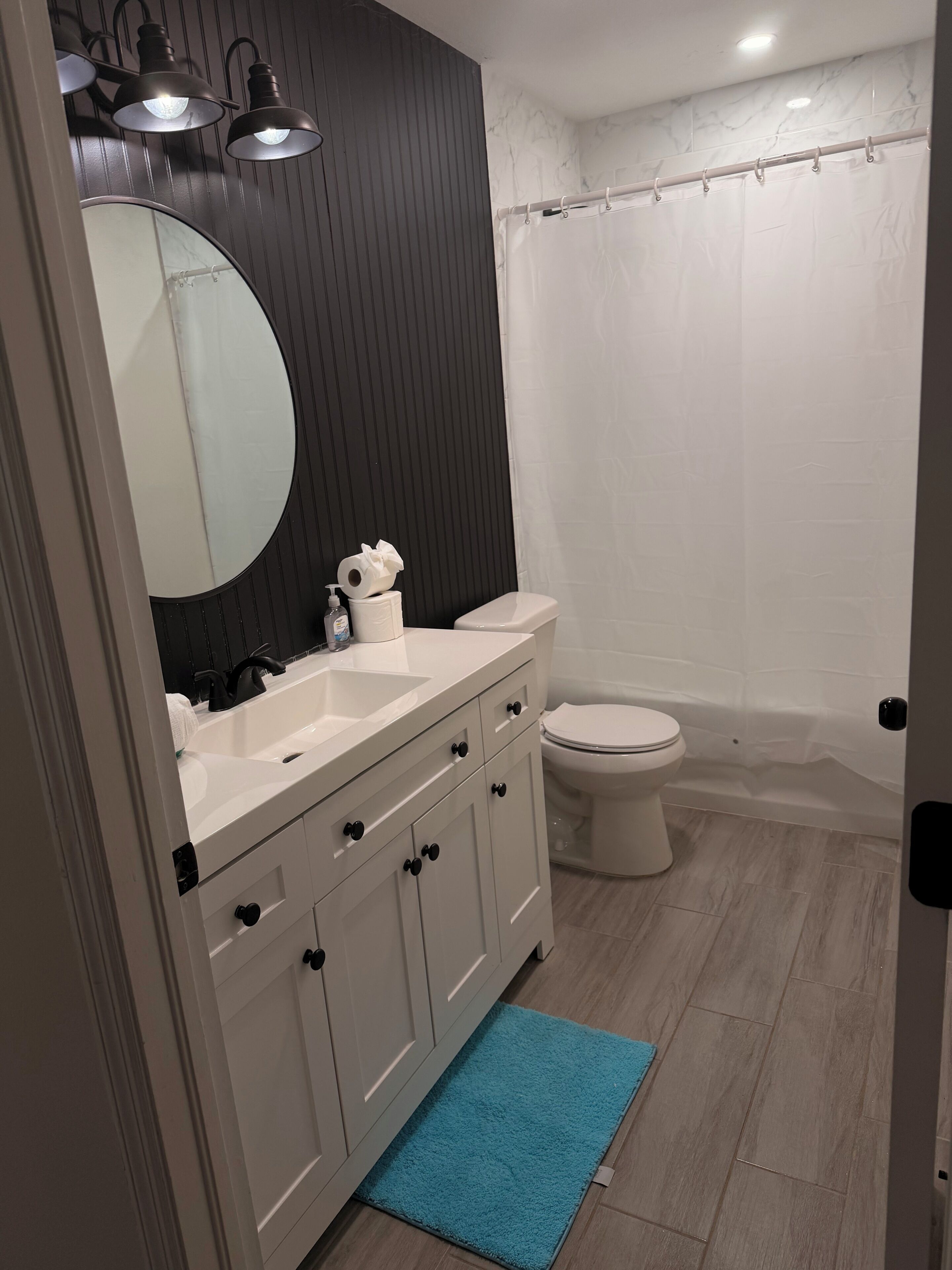 Een badkamer met een wit wastafelmeubel, toilet en douchegordijn.