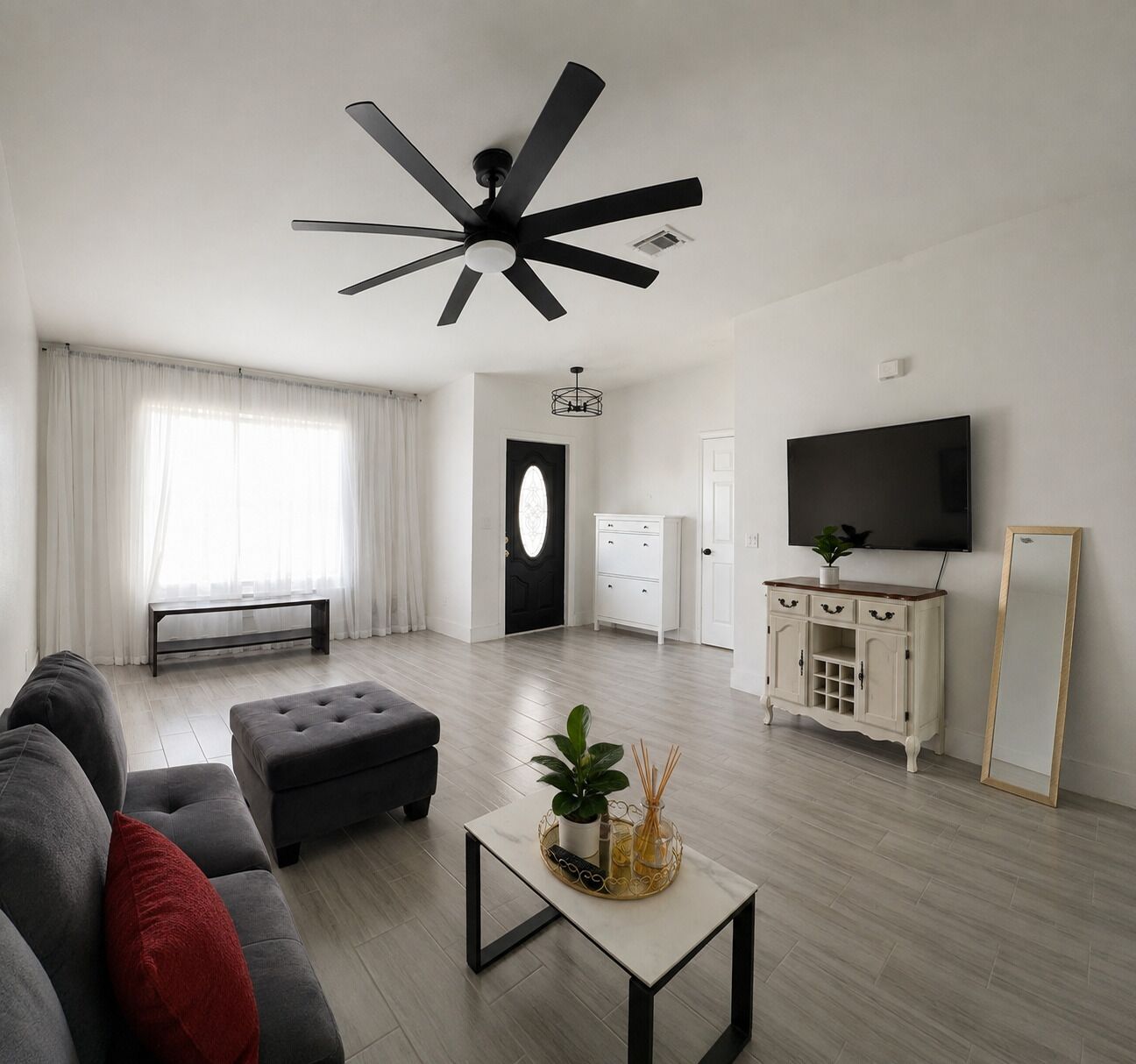 Un salon moderne avec un ventilateur de plafond, un canapé, une table basse et un téléviseur.