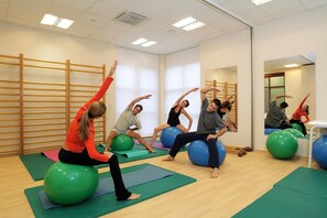 A group of people exercising on exercise balls in a room with wooden slats on the walls and a large mirror. - Svoboda Ensana Health Spa Hotel (Marianske Lazne)