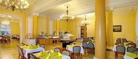 A spacious dining area with multiple tables, chairs, and a central buffet.