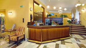 A reception area with a wooden counter, a clock, and a reception desk. - Svoboda Ensana Health Spa Hotel (Marianske Lazne)