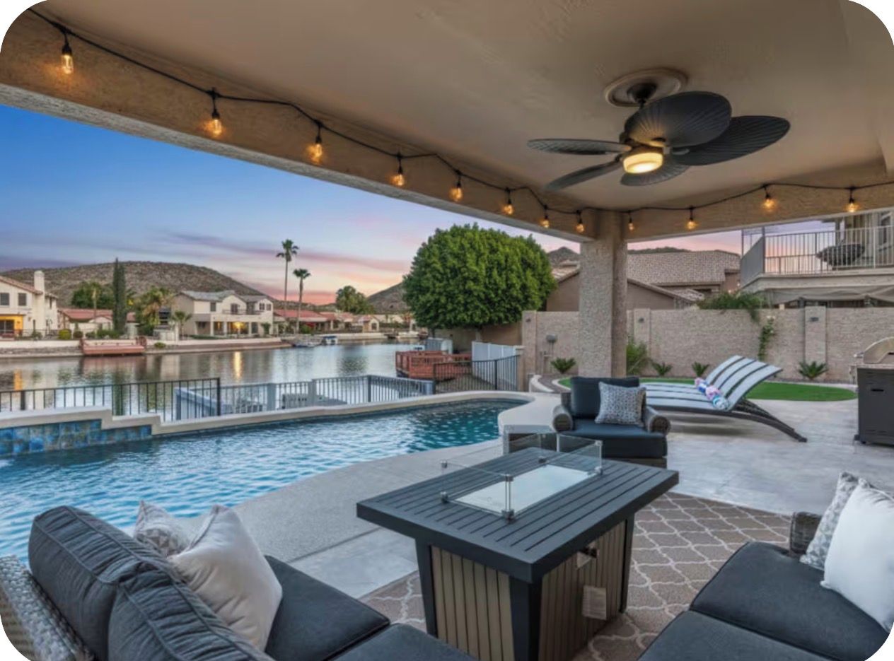 An outdoor pool area with seating and a ceiling fan.