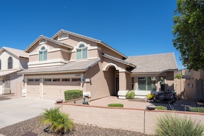 A two-story house with a garage, a covered patio, and a well-maintained front yard. - Lakefront Retreat | Free Heated Pool + Game Room (Glendale)