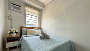Ein Schlafzimmer mit einem Bett, einem Nachttisch und einem Fenster mit Jalousien.