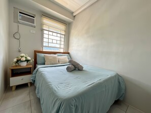 Ein Schlafzimmer mit einem Bett, einem Nachttisch und einem Fenster mit Jalousien.