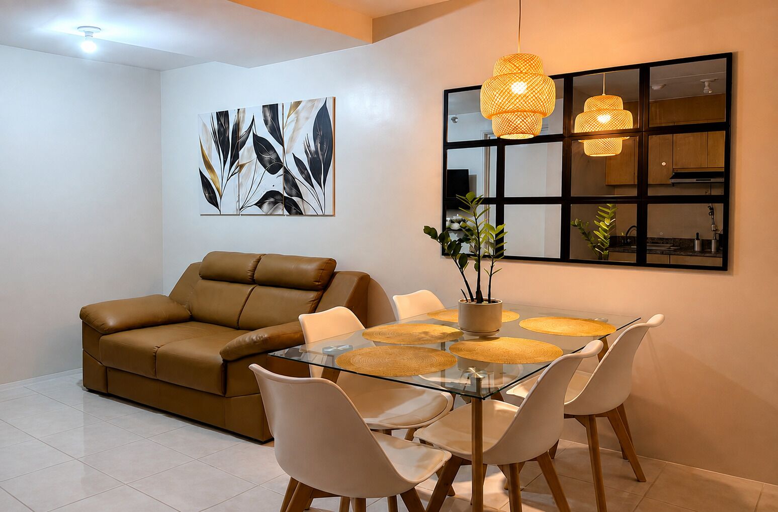 A modern living room with a glass dining table, leather sofa, and contemporary pendant lights.