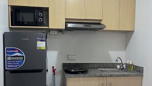 Eine kleine Küche mit Kühlschrank, Mikrowelle, Herd und Spüle.