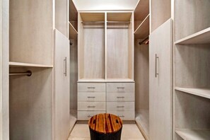 A walk-in closet with open shelving, a central storage unit with drawers, and a round wooden table. - Luxury Oceanview Condo | Hyatt PR Golf & Beach (Rio Grande)