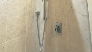 Eine Dusche mit Handbrause und fest installierter Duschkopf an der Wand.