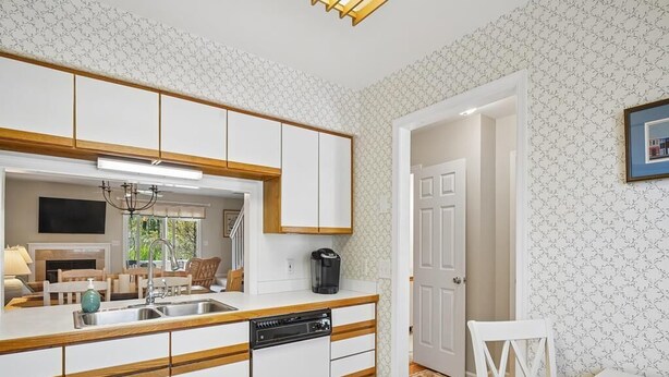 Une cuisine moderne avec des meubles blancs, un lave-vaisselle encastré et un plan de travail en bois.