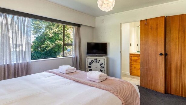 Ein Schlafzimmer mit einem Bett, einem Fernseher, einer Uhr und einem Kleiderschrank.