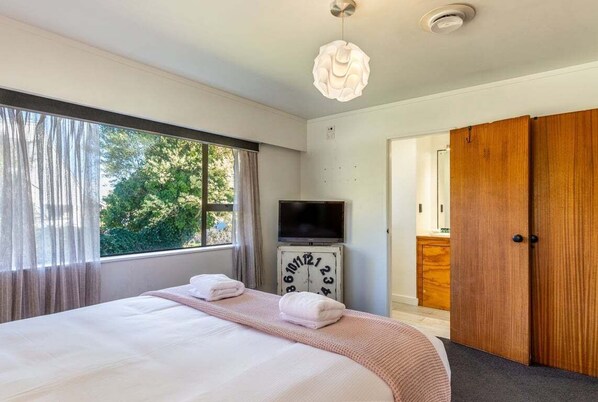A bedroom with a bed, a television, a clock, and a wardrobe.