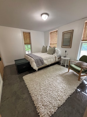 A bedroom with a bed, bedside table, chair, and a large rug. - New! “Lost on a Mountain in Maine”: Escape to this pond front mountain-retreat! (Lovell)