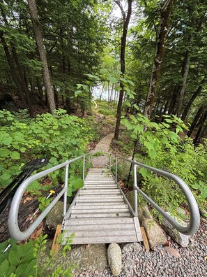 A wooden staircase with metal railings leading up a forested path.