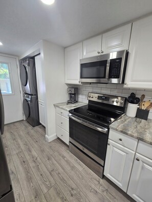 A modern kitchen with white cabinetry, a stainless steel microwave, a built-in oven, and a coffee maker. - First Floor Flat, Surf Court Villa, 2-King Beds, Steps to Coligny Beach! (Hilton Head Island)