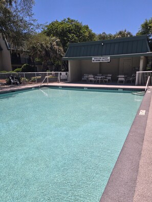 A clear pool with a shallow water sign, lounge chairs, and a covered seating area. - First Floor Flat, Surf Court Villa, 2-King Beds, Steps to Coligny Beach! (Hilton Head Island)