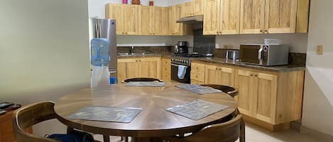 Una cocina con armarios de madera, un refrigerador, una estufa, un microondas y un dispensador de agua.