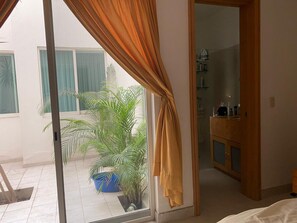 A room with a sliding glass door leading to a balcony with potted plants. - Zona Romantica 2-bedroom condo in  Puerto Vallarta with AC (Puerto Vallarta)