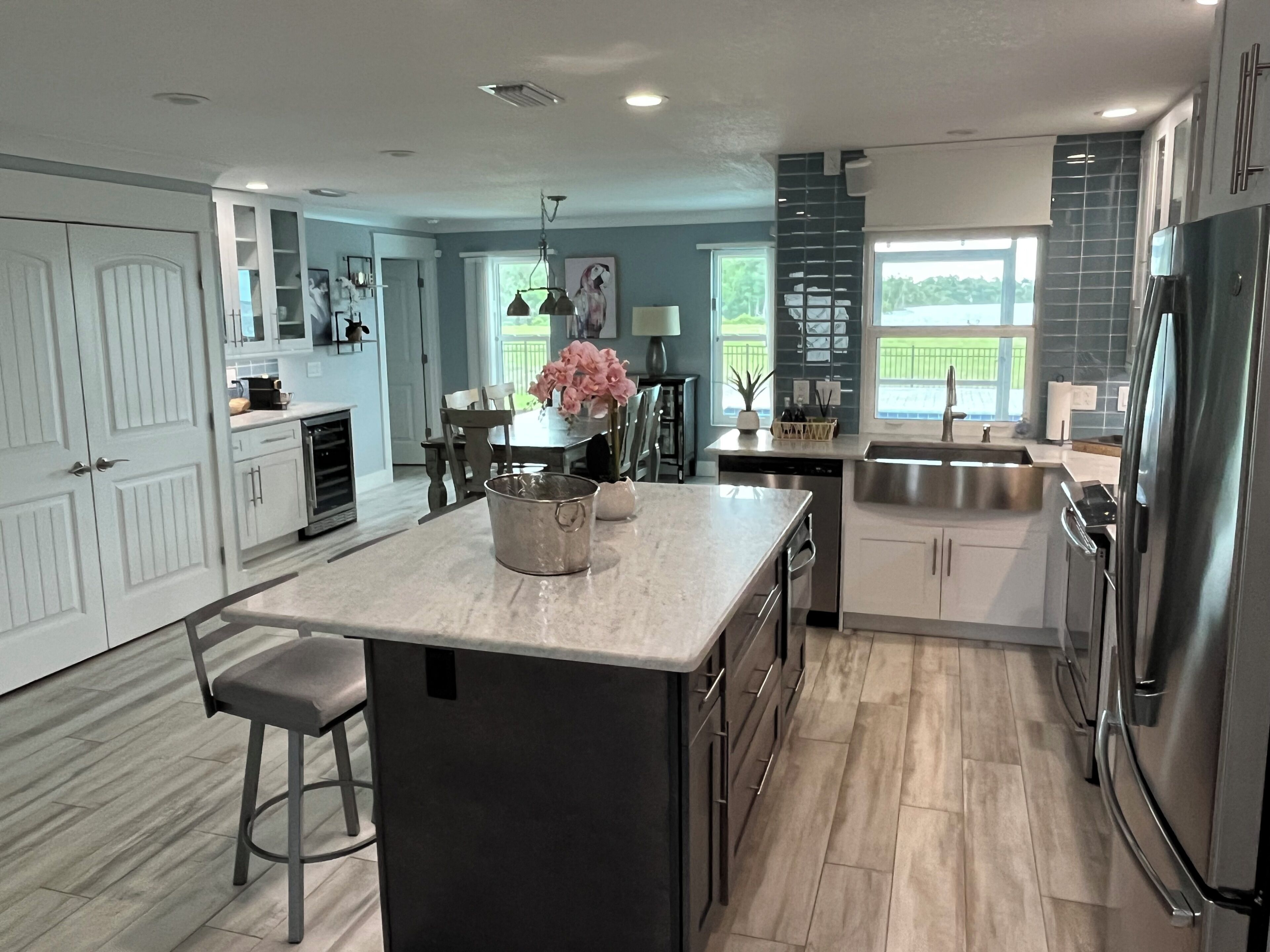 A modern kitchen with a central island, stainless steel appliances, and a view of the outdoors.